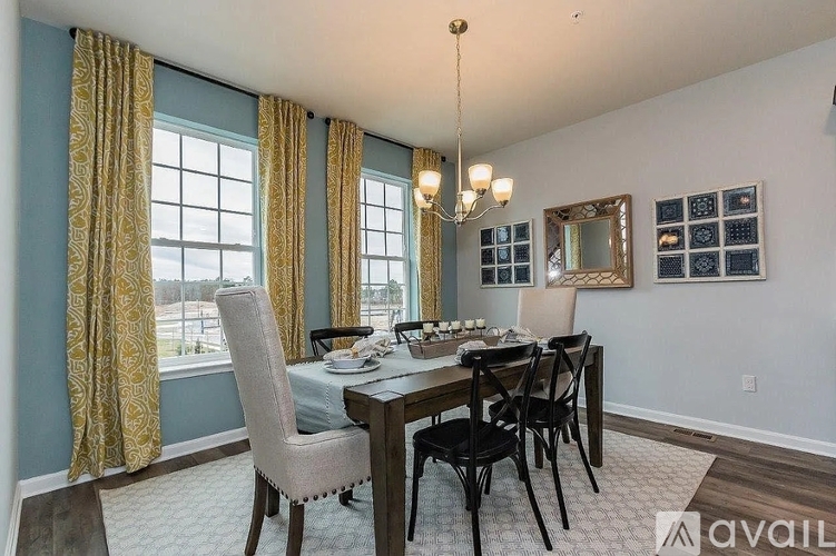 A dining room with a table set for four and a chandelier hanging from the ceiling.