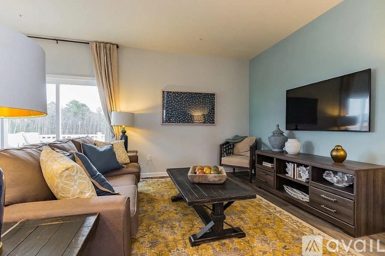 A living room with a brown couch, a coffee table, and a flat screen TV mounted on the wall.