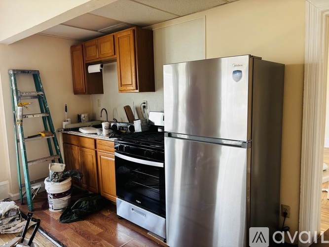 A kitchen with a stainless steel refrigerator and wooden cabinets.