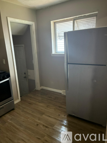 A kitchen with a stainless steel refrigerator and wooden flooring.