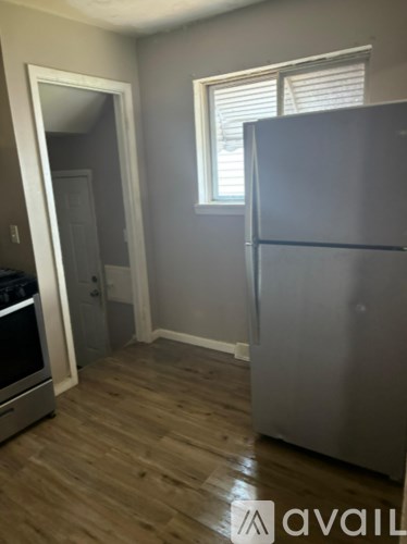 A kitchen with a stainless steel refrigerator and wooden flooring.