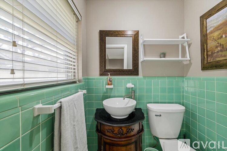 A bathroom with green tiles and a white toilet.