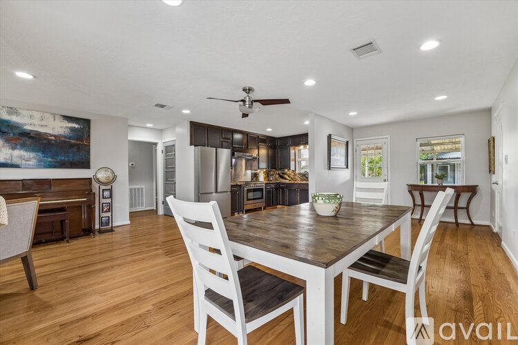 A modern dining room with a wooden table and white chairs.