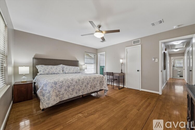 A bedroom with a bed, a ceiling fan, and a wooden floor.