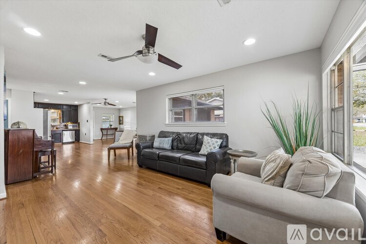 A spacious living room with a grey couch and wooden floors.
