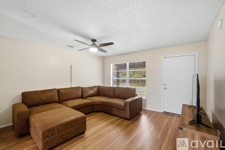 A living room with a brown leather couch and a television.