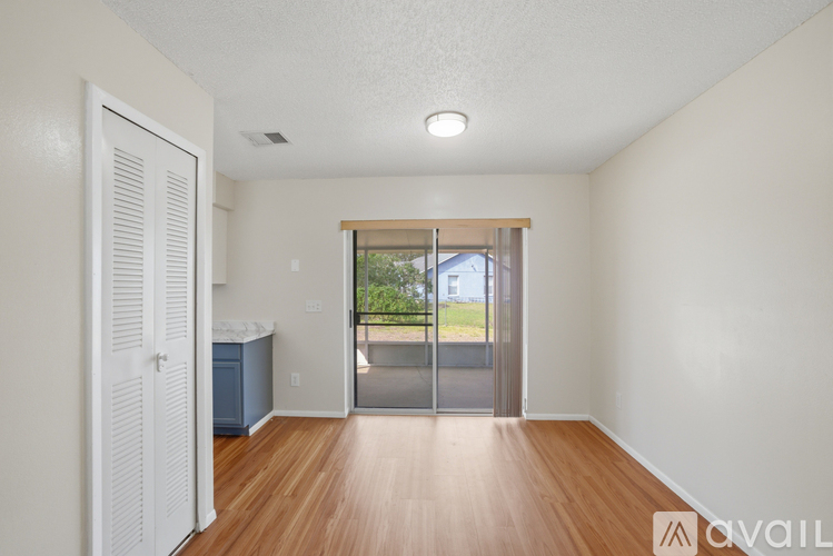 A room with a wooden floor and a sliding glass door leading to a patio.