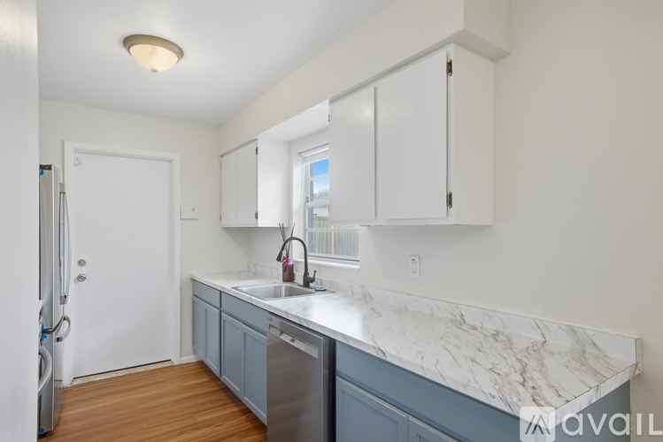 A kitchen with white cabinets and a marble countertop.