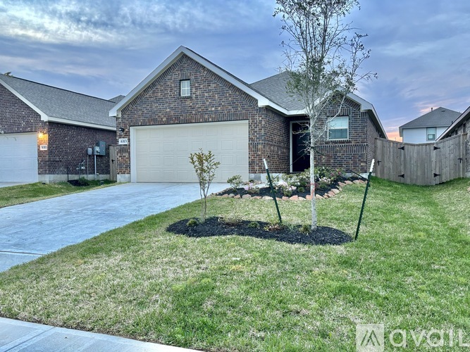 A house with a garage and a tree in the front yard.