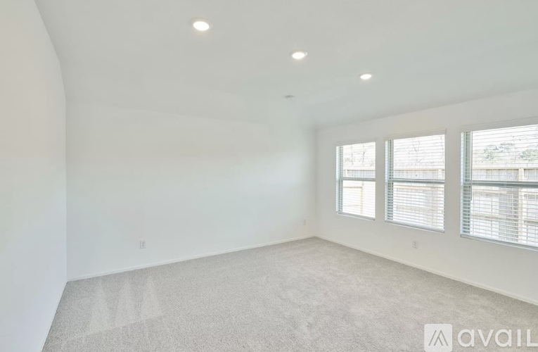 A spacious room with a carpeted floor and large windows.