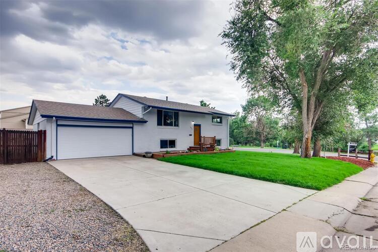 A house with a driveway and a tree in front of it.