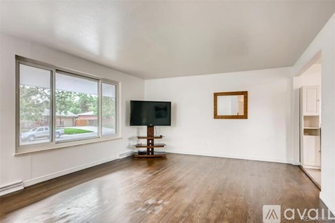 A spacious living room with a television and a window overlooking a street.