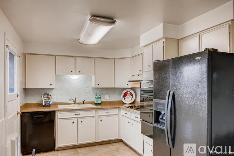 A kitchen with white cabinets and a black fridge.