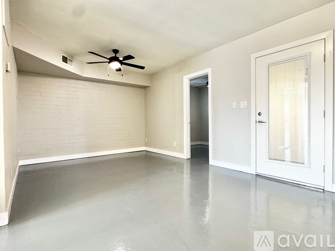 A spacious room with a ceiling fan and a door leading to another room.