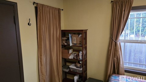 A room with a brown curtain and a bookshelf filled with books and other items.