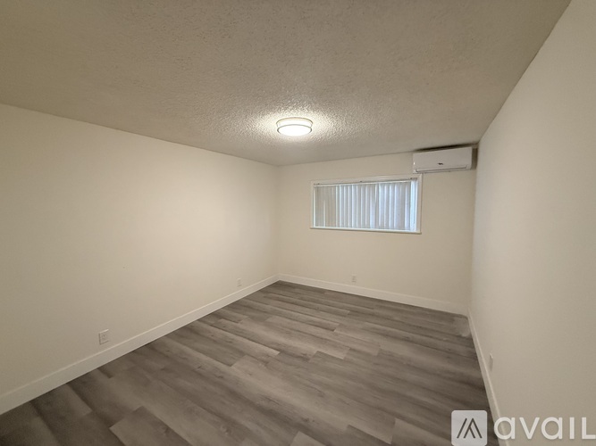 A room with wooden flooring and a window with blinds.