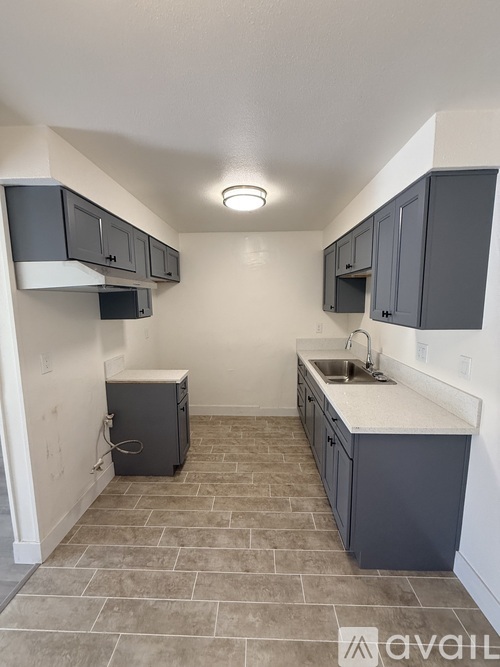 A kitchen with grey cabinets and a white countertop.