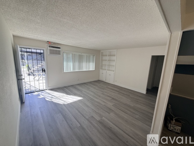 A room with a sliding glass door and wooden flooring.