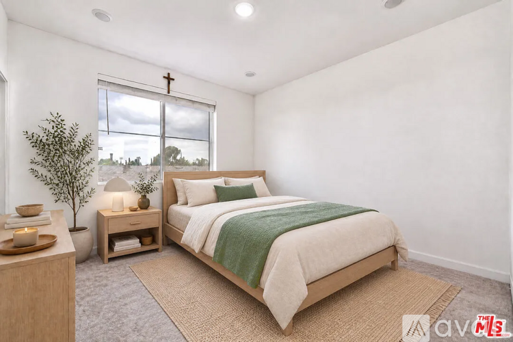 A bedroom with a large bed and a cross on the window.