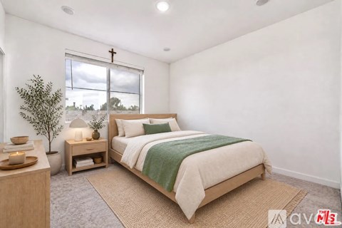 A bedroom with a large bed and a cross on the window.