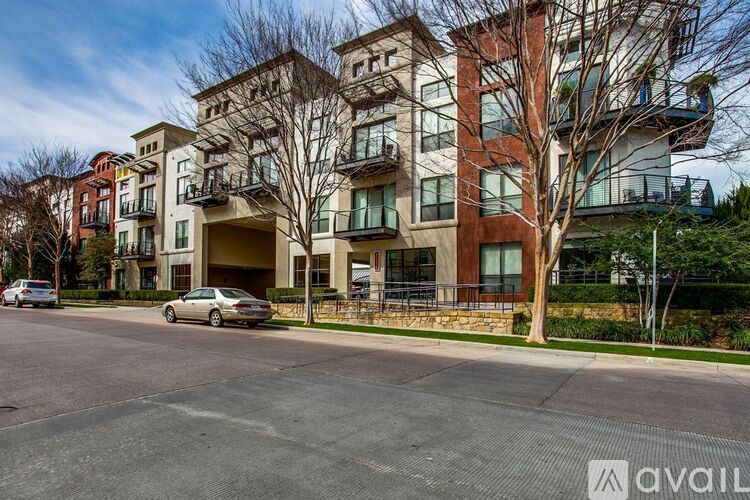 A car is parked in front of a multi-story apartment building.