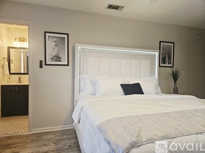 A bedroom with a large bed and a framed picture of a lighthouse on the wall.