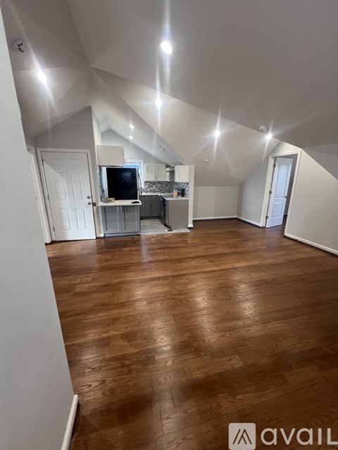 A spacious room with wooden flooring and white walls.
