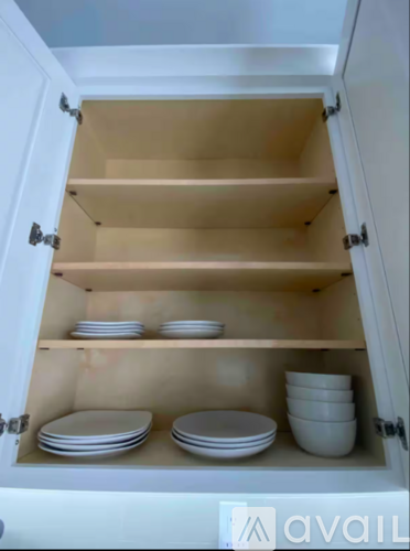 A white cabinet with plates and bowls on the shelves.