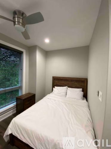 A bedroom with a bed, nightstand, and window with blinds.