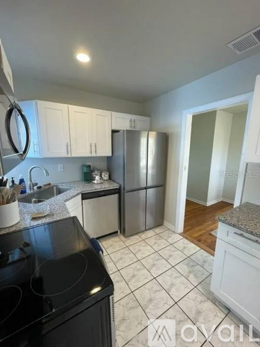 A kitchen with a black stove top oven and white cabinets.