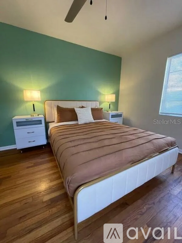 A bedroom with a bed, nightstands, and a ceiling fan.