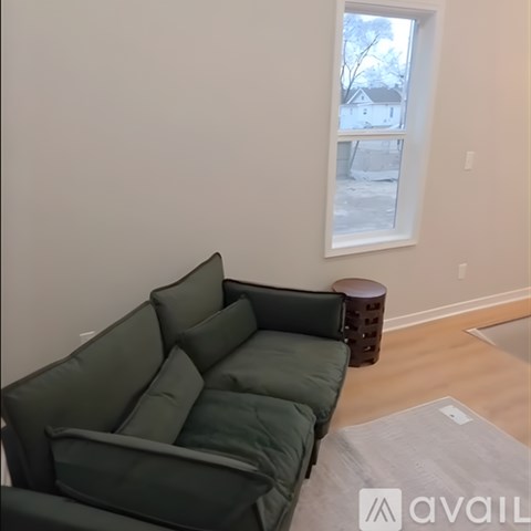 A green couch in a room with a window.