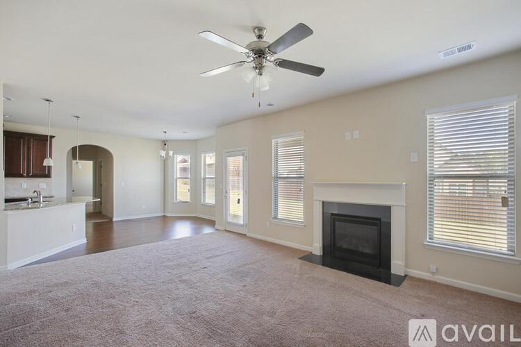 A spacious living room with a fireplace and a ceiling fan.