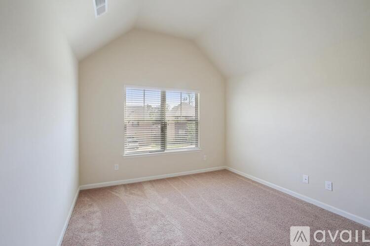 A room with a carpeted floor and a window with blinds.