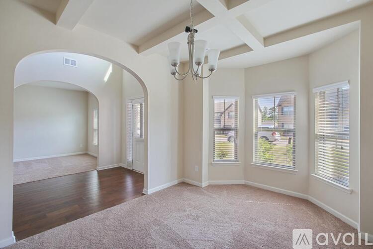 A spacious room with a chandelier and large windows.