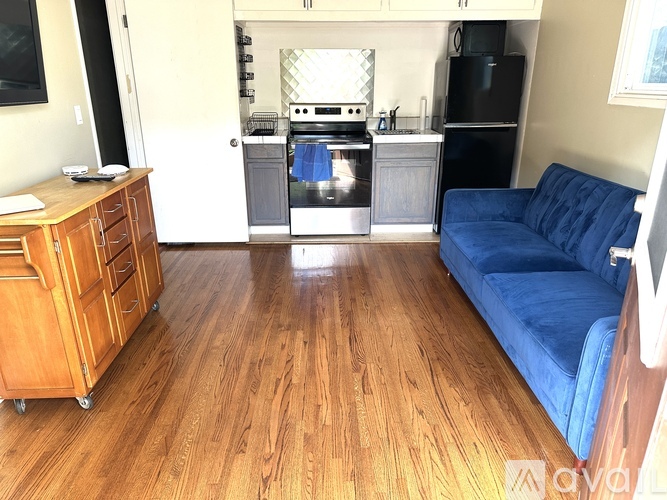 A kitchen with a blue couch and wooden floors.