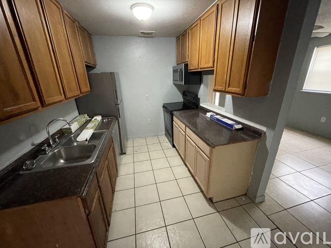 A kitchen with wooden cabinets and a black refrigerator.
