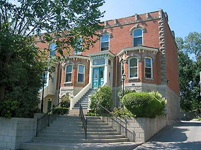 A red brick house with a green door and steps leading up to it.