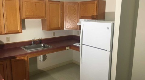 A white refrigerator stands in a kitchen with wooden cabinets.