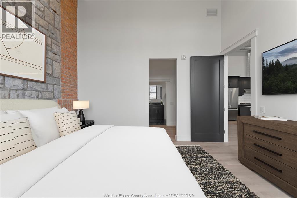 A bedroom with a large bed and a television on the wall.