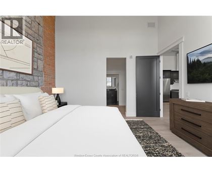 A bedroom with a large bed and a television on the wall.
