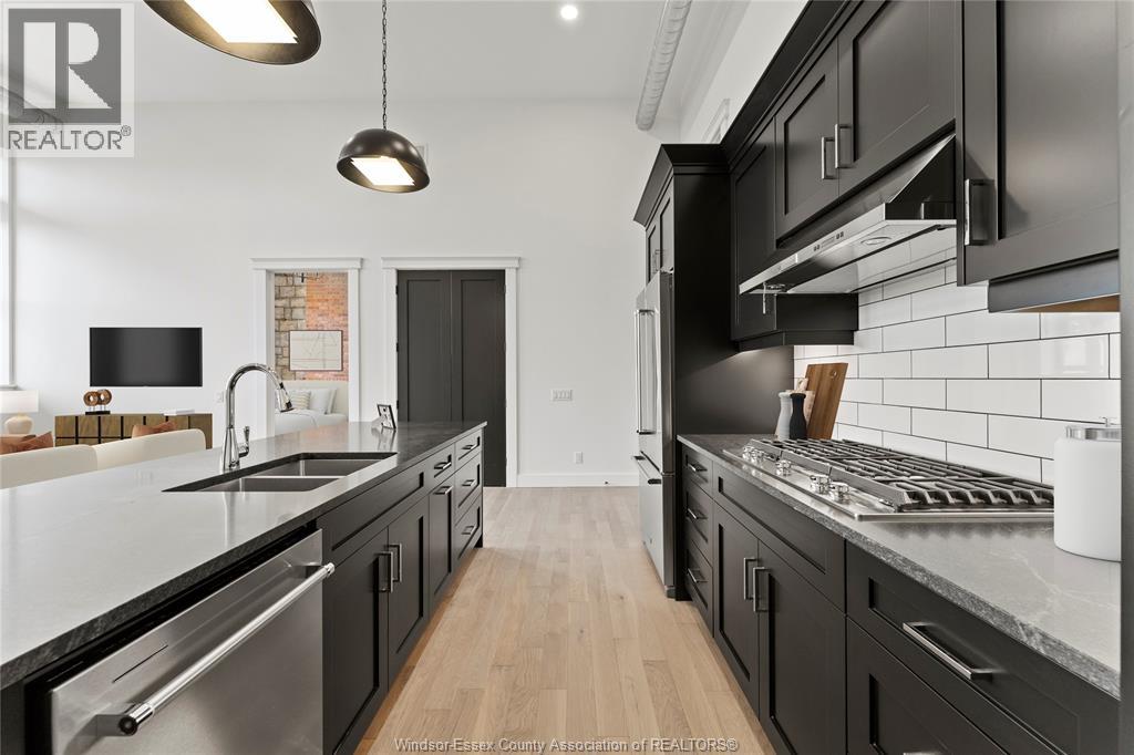 A modern kitchen with black cabinets and stainless steel appliances.