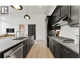 A modern kitchen with black cabinets and stainless steel appliances.