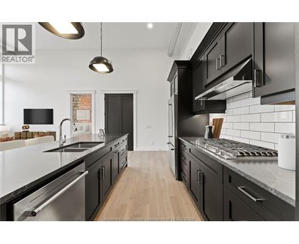 A modern kitchen with black cabinets and stainless steel appliances.