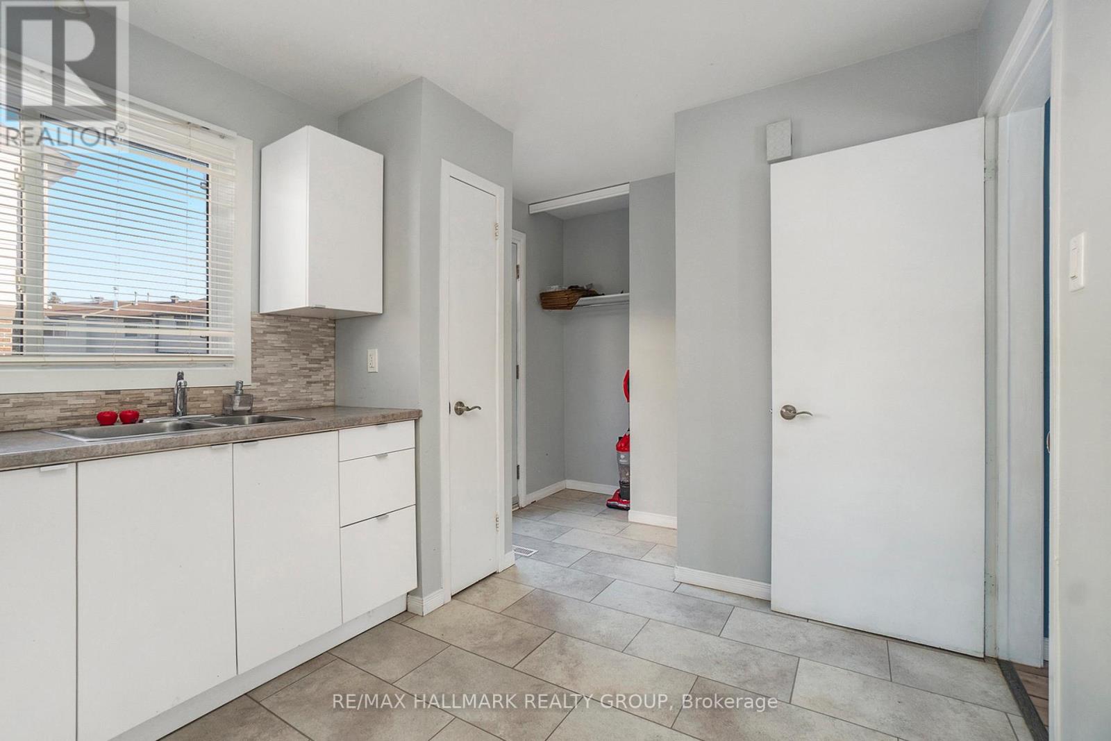 A kitchen with white cabinets and a tiled floor.