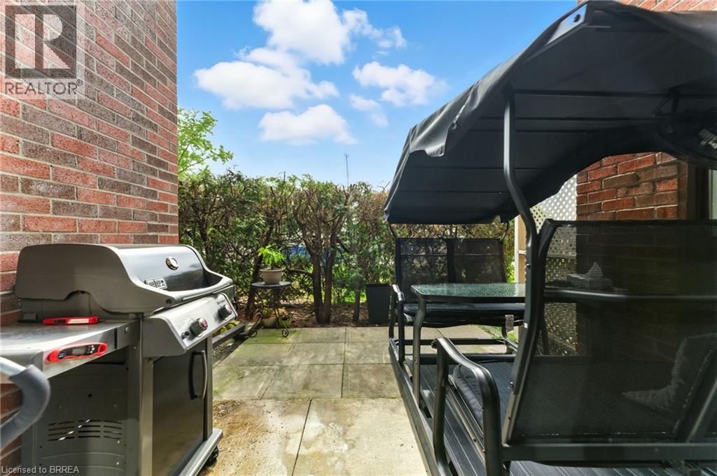 A BBQ grill is situated on a patio next to a brick wall.