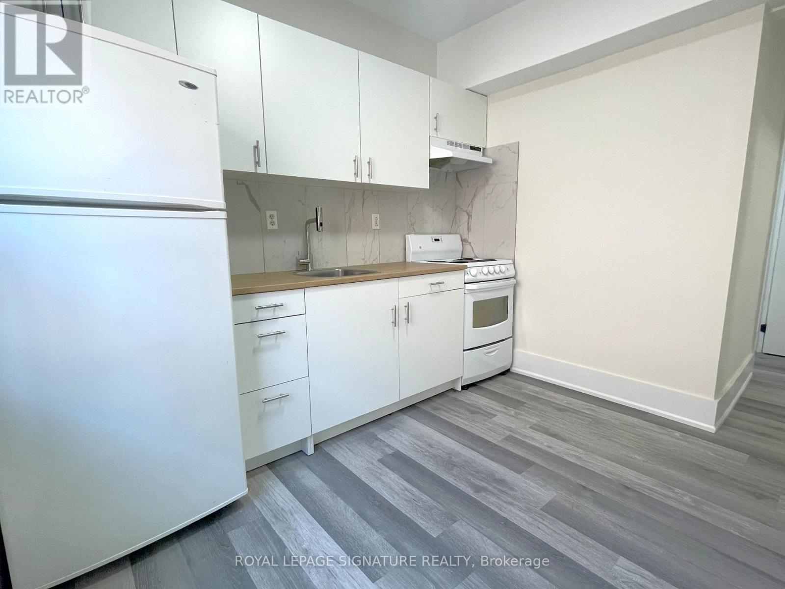 A kitchen with white cabinets and a white fridge.