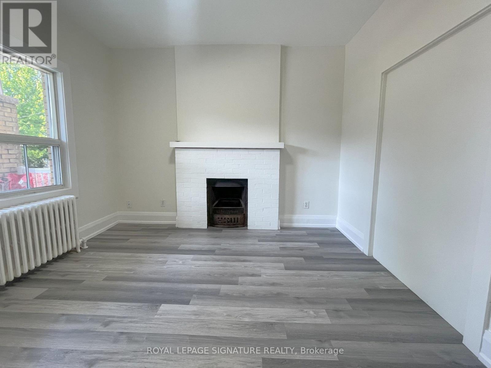 A room with a fireplace and wooden flooring.