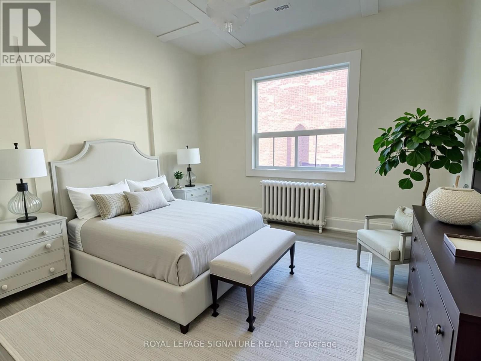 A bedroom with a large bed, a window, and a potted plant.