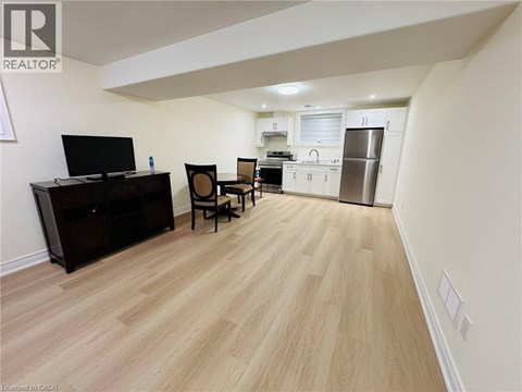 A living room with a television, chair, and a kitchen area in the background.